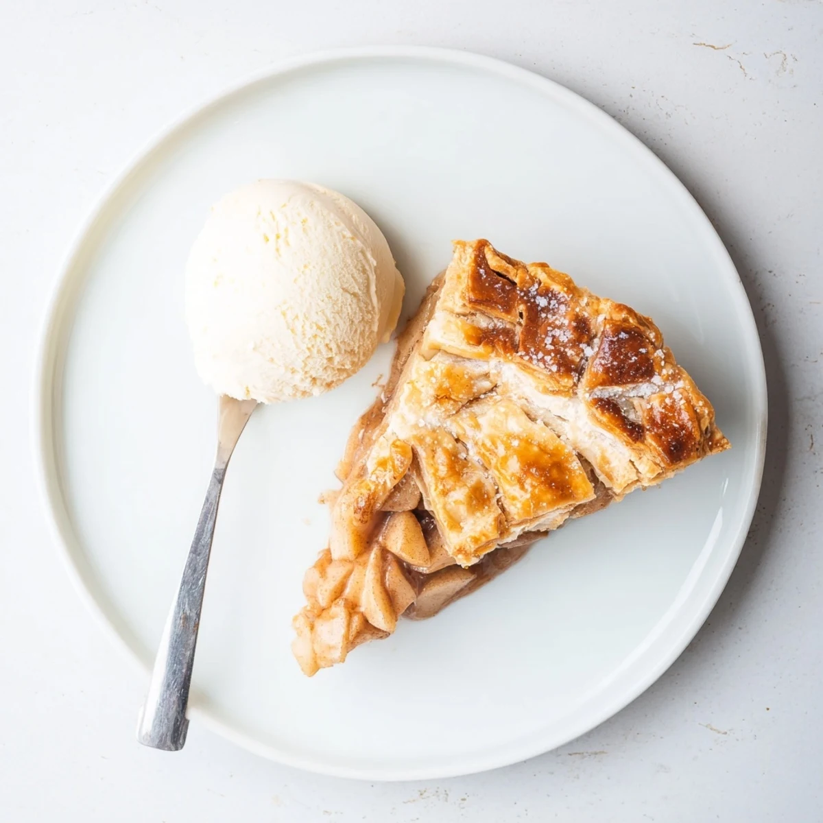 Freshly baked apple pie with a golden flaky crust is sliced to reveal tender spiced apples inside.
