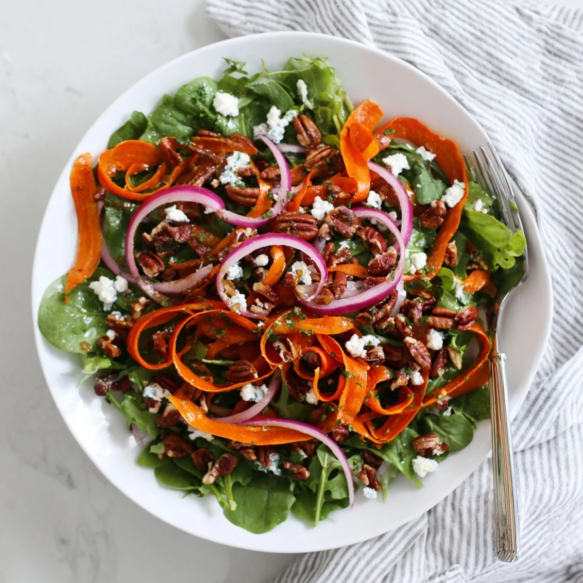 A close-up of Roasted Carrot Ribbon Salad featuring glistening carrot ribbons, fresh herbs, and a tangy vinaigrette.