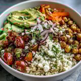 Vibrant Simple Grain Bowl with brown rice, grilled chicken, cucumbers, carrots, feta, and a lemony dressing, ready for a healthy lunch.