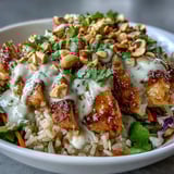 Colorful medley of vegetables and greens fills a Peanut Chicken Power Bowl, with golden chicken and a drizzle of rich peanut sauce, ready for a satisfying meal.