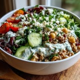 A hearty Mediterranean Farro Bowl with chickpeas and vibrant veggies, drizzled with lemon tahini sauce on a rustic wooden table.