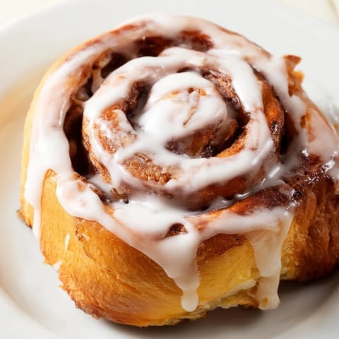 Warm Cinnamon Rolls are drizzled with sweet vanilla icing, paired with coffee, making a cozy breakfast treat.
