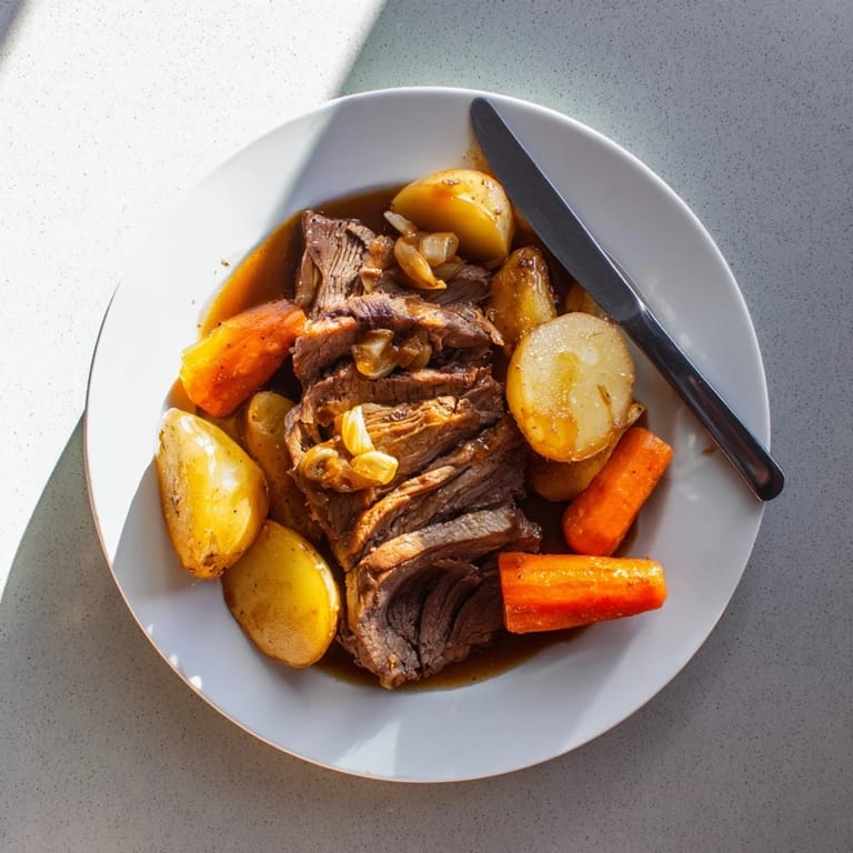 Golden Beef Pot Roast sliced on a platter with roasted vegetables and fresh thyme garnish.