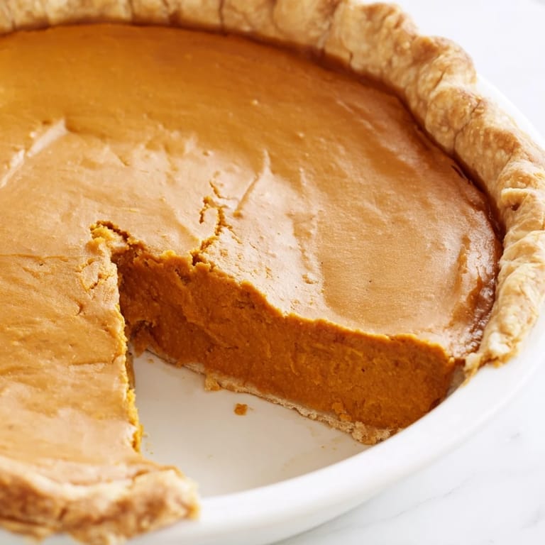 Holiday Pumpkin Pie cooling on a wire rack, showcasing its deep, caramelized surface and cozy autumn spices like cinnamon and nutmeg.