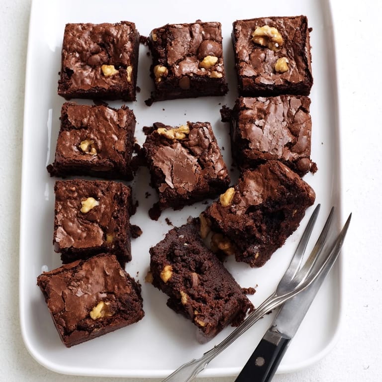 Freshly baked Brownies show gooey centers and chopped walnuts on a rustic wooden table. 