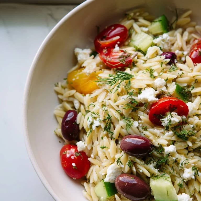 Hearty Greek Orzo Salad featuring tender pasta, Kalamata olives, and fresh herbs, ready for a summer potluck.
