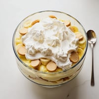 Close-up of Banana Pudding layered in a glass trifle bowl, showing vanilla wafers, fresh banana slices, and creamy pudding.