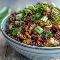 Ground beef and cabbage stir-fry in a hot wok, coated in savory umami sauce with garlic and ginger.
