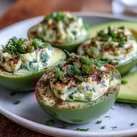 Green avocado deviled eggs with fresh herbs and paprika garnish.  